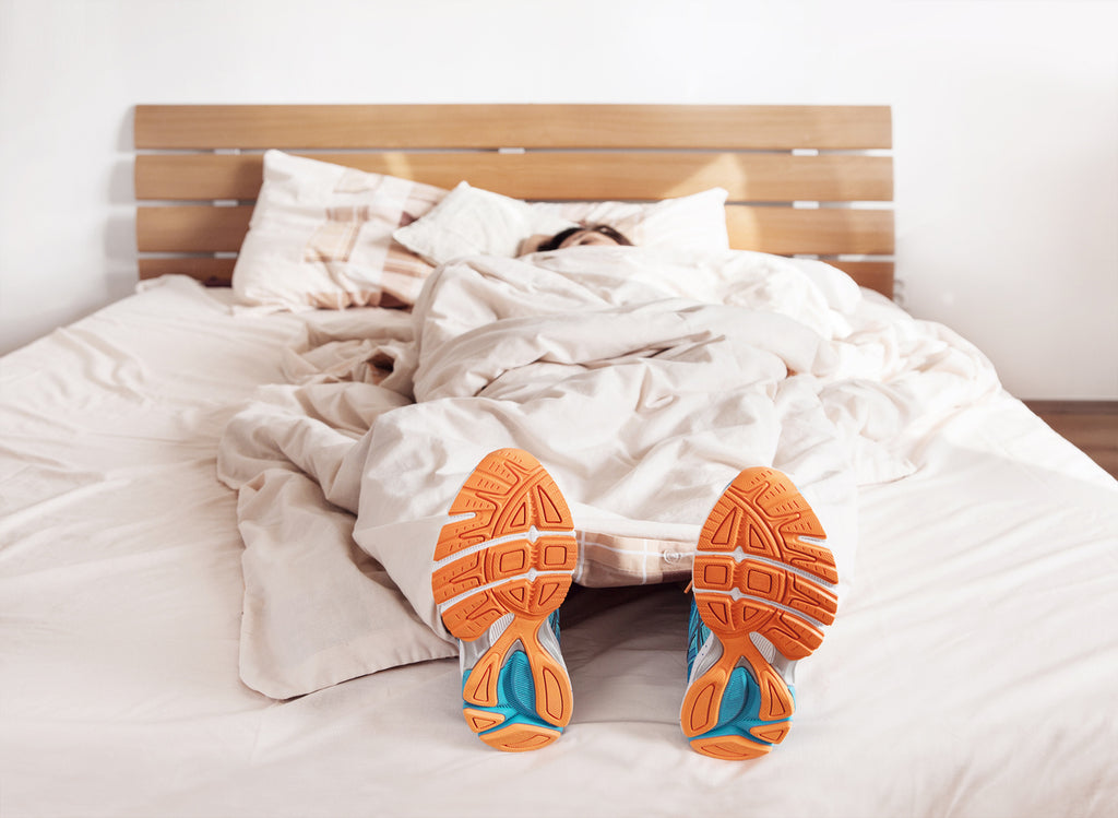 Woman in bed wearing running shoes - mattress is your most important personal fitness tool concept