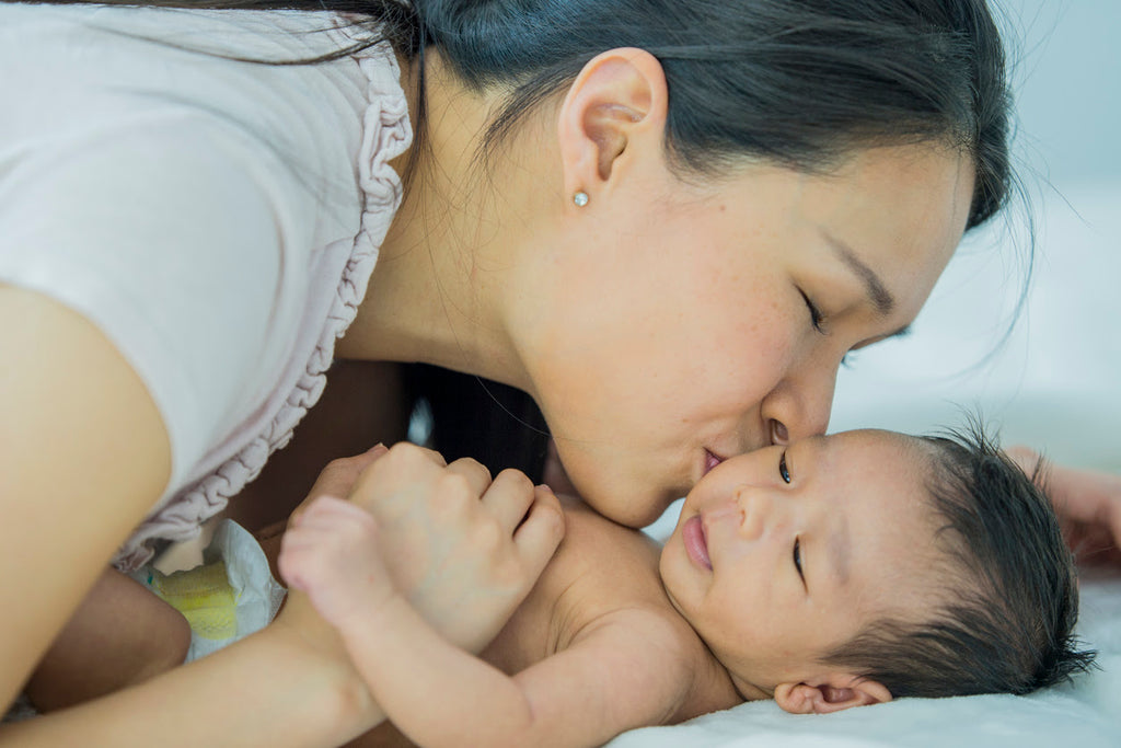 Mother kissing infant son putting him to sleep