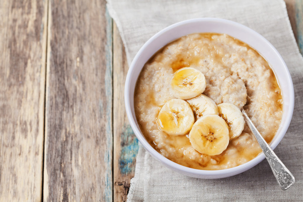 bowl of oatmeal with honey and bananas on wooden table