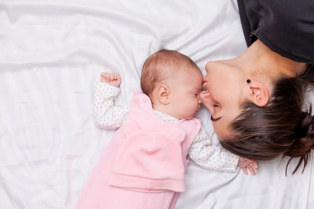 Happy mother and infant daughter on a new mattress