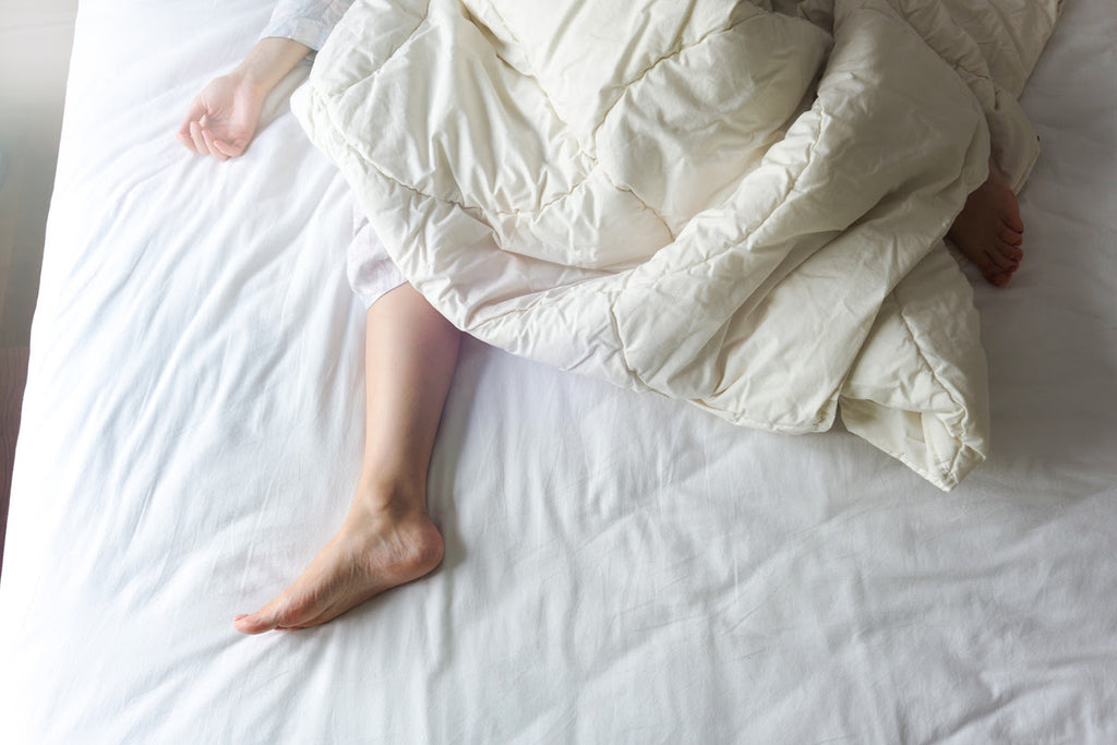 Bare Feet of a Young Woman on White Bed and New Mattress - Sleep Patterns Concept