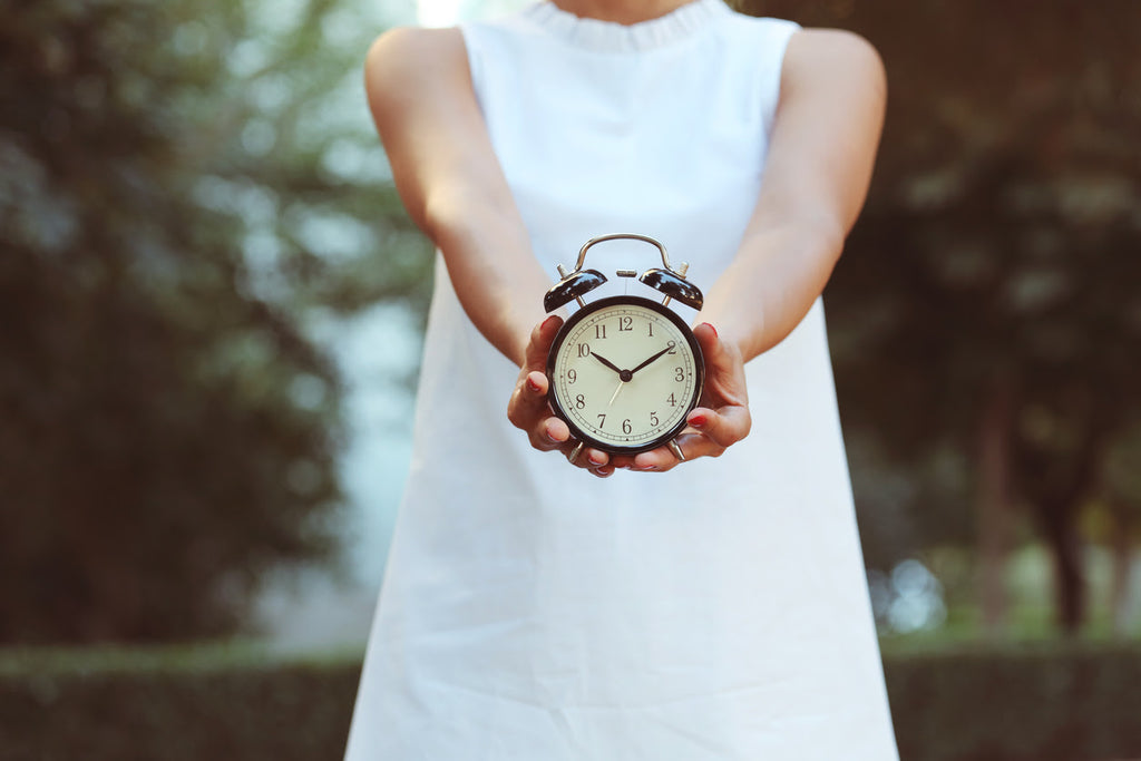 Woman holding out an alarm clock - resetting your body clock concept